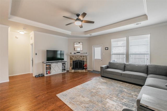 537 Running Water Trl, Fort Worth, TX 76131 - living room featuring a tray ceiling, ceiling fan, wood finished floors, ornamental molding, and a stone fireplace
