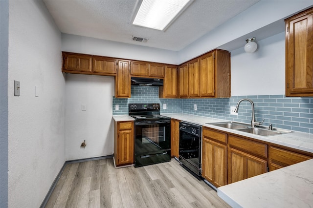 kitchen featuring black appliances, brown cabinetry, a sink, and under cabinet range hood