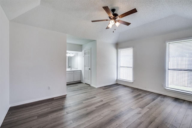 spare room with a ceiling fan, lofted ceiling, baseboards, and wood finished floors