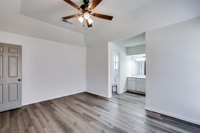spare room featuring a textured ceiling, wood finished floors, a ceiling fan, visible vents, and baseboards