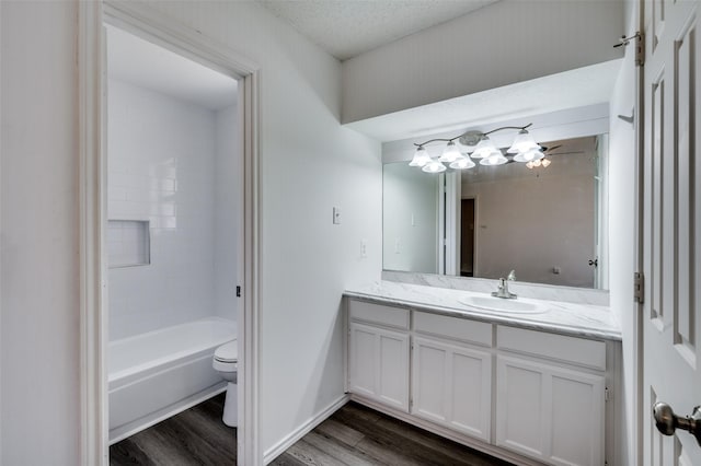bathroom featuring toilet, wood finished floors, bathtub / shower combination, a textured ceiling, and vanity