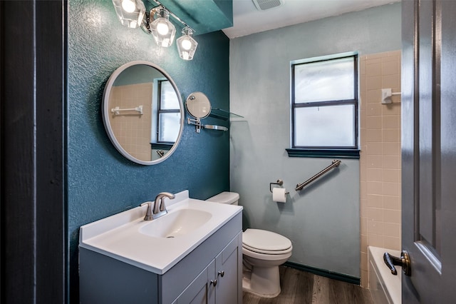 bathroom with a textured wall, vanity, wood finished floors, and toilet