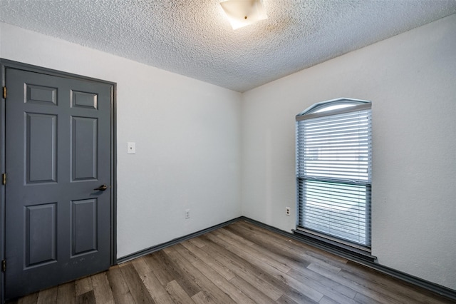 empty room with a textured ceiling and wood finished floors
