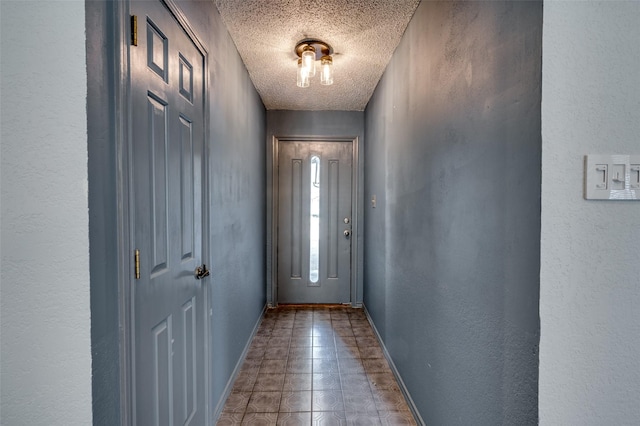 entryway with a textured ceiling, a textured wall, and baseboards