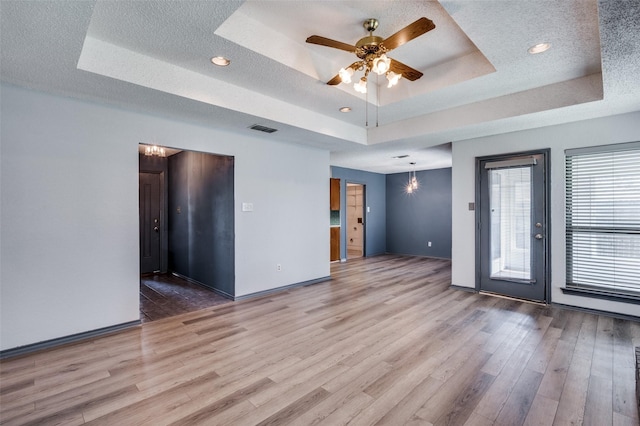 unfurnished room featuring visible vents, a raised ceiling, and wood finished floors