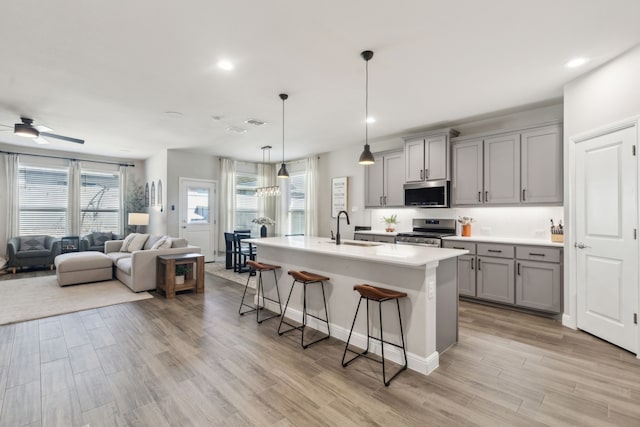 kitchen featuring open floor plan, stainless steel appliances, light countertops, a kitchen bar, and a sink