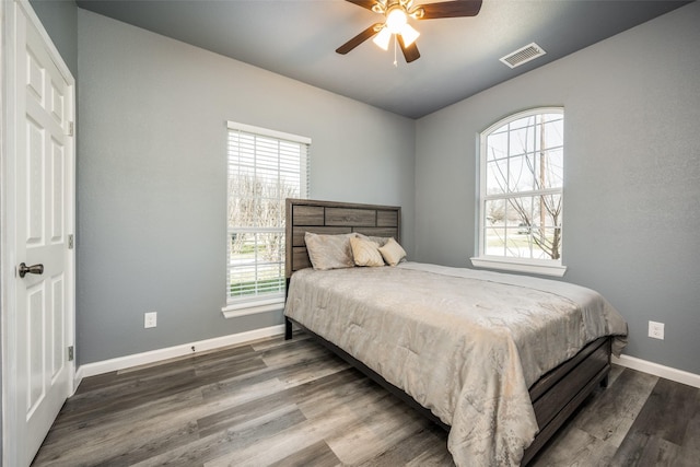 bedroom featuring a ceiling fan, dark wood-style flooring, visible vents, and baseboards