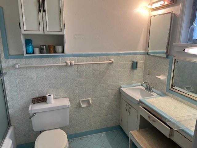 full bath featuring tile patterned flooring, toilet, a wainscoted wall, vanity, and combined bath / shower with glass door