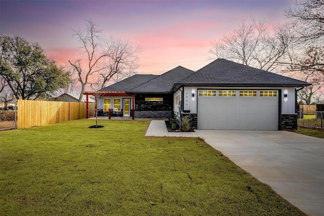 view of front of house with fence, driveway, an attached garage, and a lawn