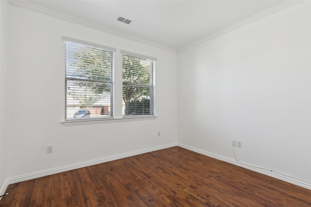 empty room with baseboards, visible vents, crown molding, and wood finished floors