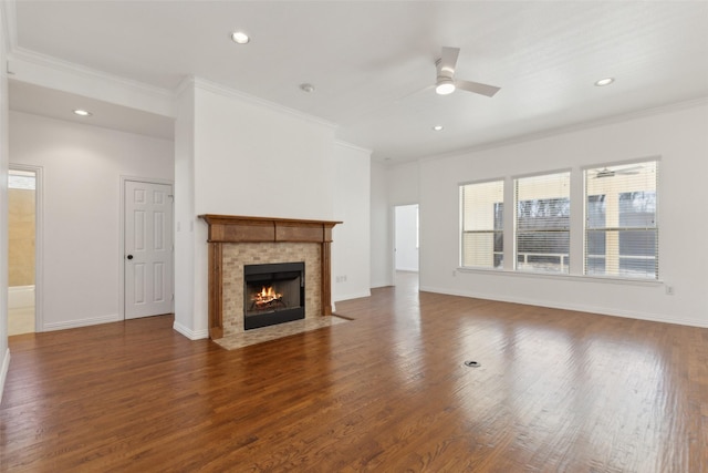 unfurnished living room featuring baseboards, a tiled fireplace, ornamental molding, and dark wood-type flooring