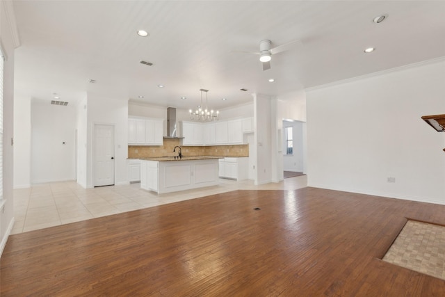 unfurnished living room featuring recessed lighting, ceiling fan with notable chandelier, a sink, ornamental molding, and light wood-type flooring