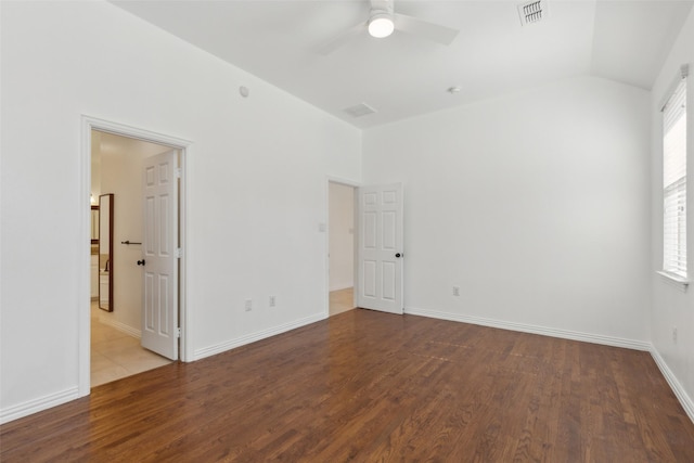 empty room with lofted ceiling, wood finished floors, a ceiling fan, visible vents, and baseboards