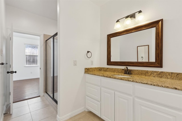 full bathroom with a stall shower, tile patterned flooring, vanity, and baseboards