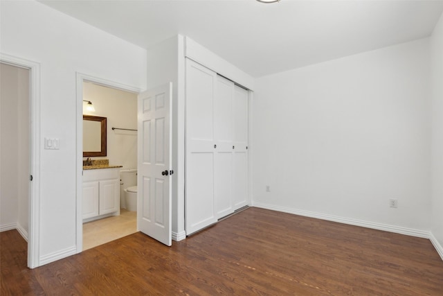 unfurnished bedroom with dark wood-style floors, a closet, and baseboards