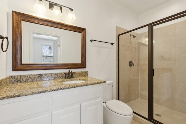 bathroom featuring toilet, a shower stall, and vanity