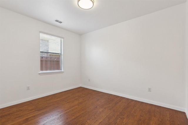 empty room featuring baseboards, visible vents, and wood finished floors