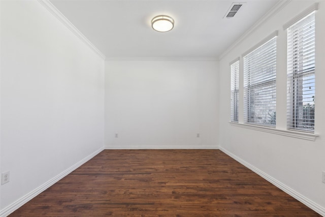 empty room featuring baseboards, dark wood-style flooring, visible vents, and crown molding