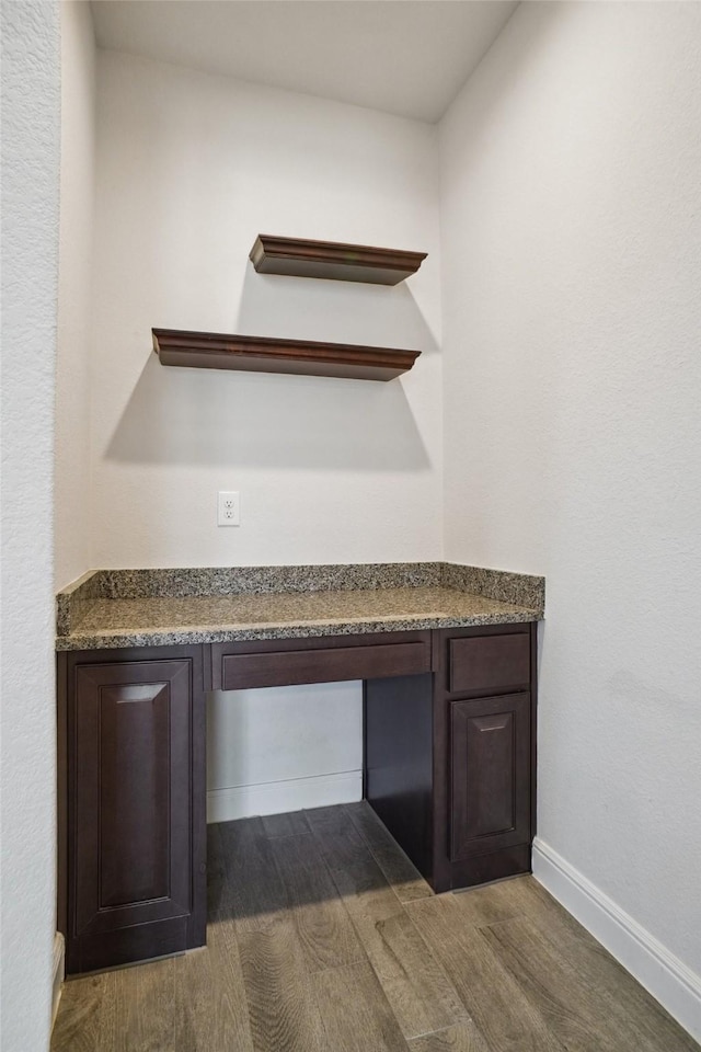 interior details with built in desk, baseboards, and wood finished floors