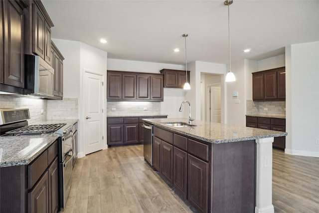 kitchen featuring a center island with sink, appliances with stainless steel finishes, pendant lighting, and a sink