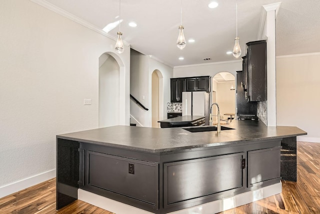 kitchen featuring crown molding, dark countertops, and a sink