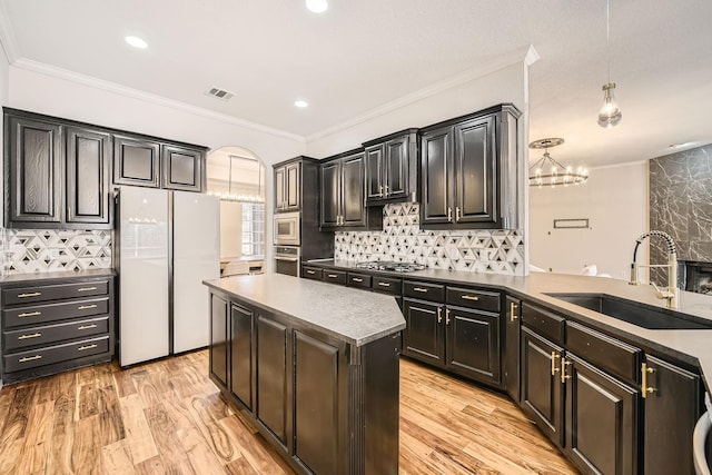 kitchen featuring light wood finished floors, visible vents, appliances with stainless steel finishes, ornamental molding, and a sink