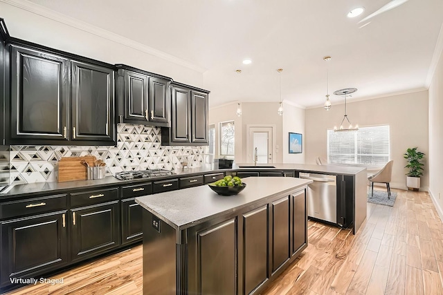 kitchen with crown molding, stainless steel appliances, tasteful backsplash, dark cabinets, and a peninsula