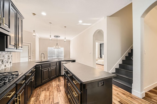 kitchen featuring light wood-style floors, crown molding, and a sink