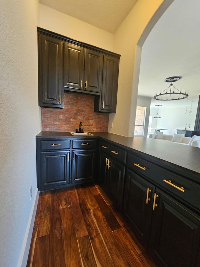 bar featuring decorative backsplash, arched walkways, dark wood-type flooring, and a sink