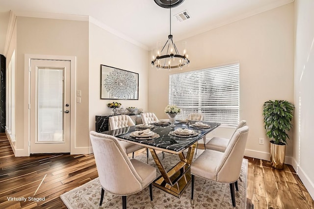 dining space featuring visible vents, ornamental molding, wood finished floors, a chandelier, and baseboards