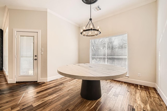 unfurnished dining area featuring visible vents, baseboards, dark wood finished floors, ornamental molding, and an inviting chandelier