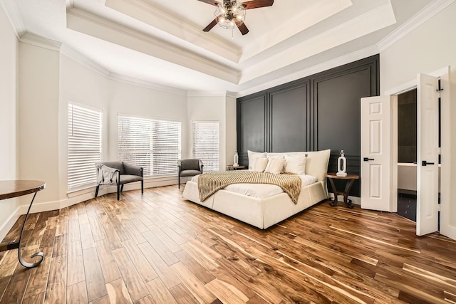 bedroom featuring ornamental molding, ceiling fan, a tray ceiling, and wood finished floors