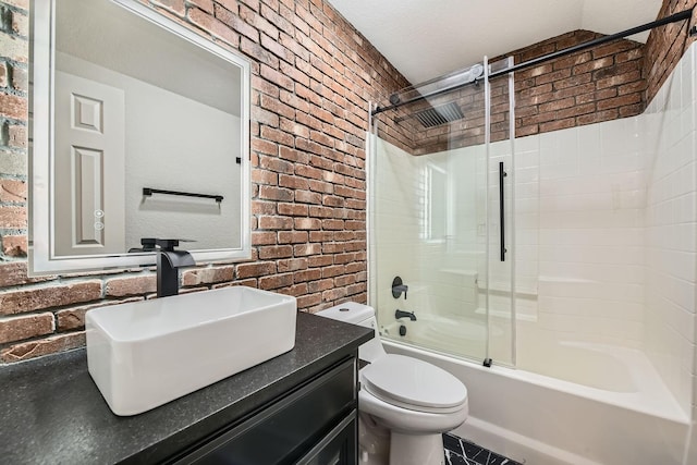 full bath with brick wall, enclosed tub / shower combo, vanity, and toilet