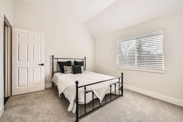 bedroom featuring lofted ceiling, baseboards, and carpet