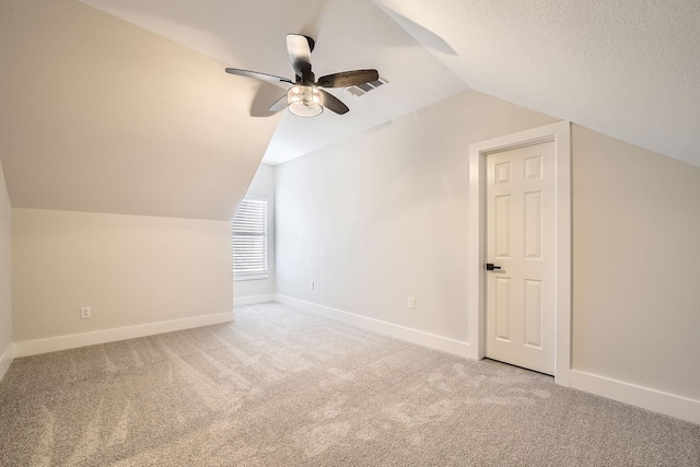 additional living space featuring carpet, vaulted ceiling, a textured ceiling, and baseboards