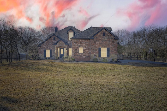 view of front of property featuring stone siding, a chimney, a front lawn, and brick siding