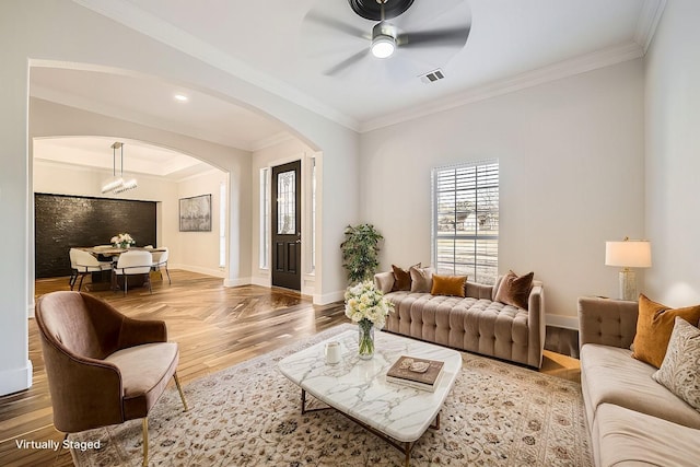 living area with baseboards, visible vents, arched walkways, ornamental molding, and wood finished floors