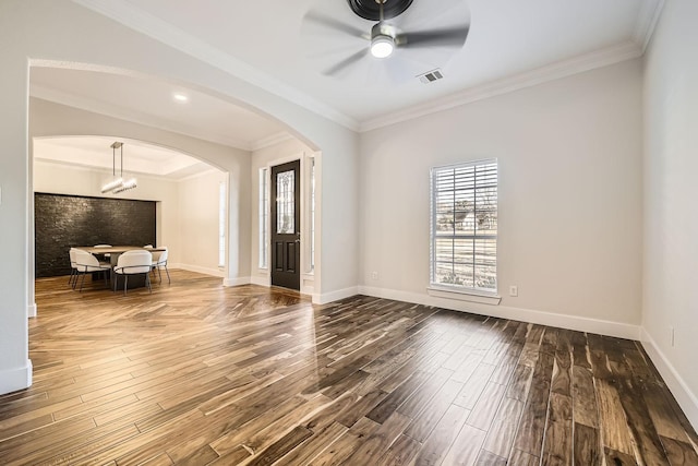 spare room with arched walkways, dark wood-style flooring, visible vents, and crown molding