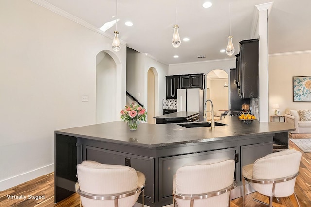 kitchen with wood finished floors, a sink, freestanding refrigerator, dark countertops, and crown molding