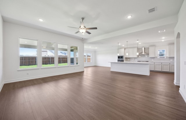 unfurnished living room featuring plenty of natural light, recessed lighting, dark wood-type flooring, and ceiling fan