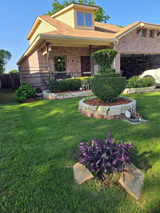 view of front of property with a garage, covered porch, a front yard, and brick siding