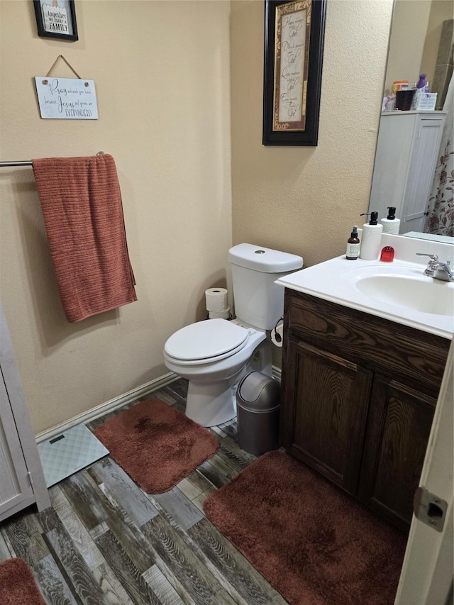 bathroom featuring toilet, wood finished floors, vanity, and baseboards