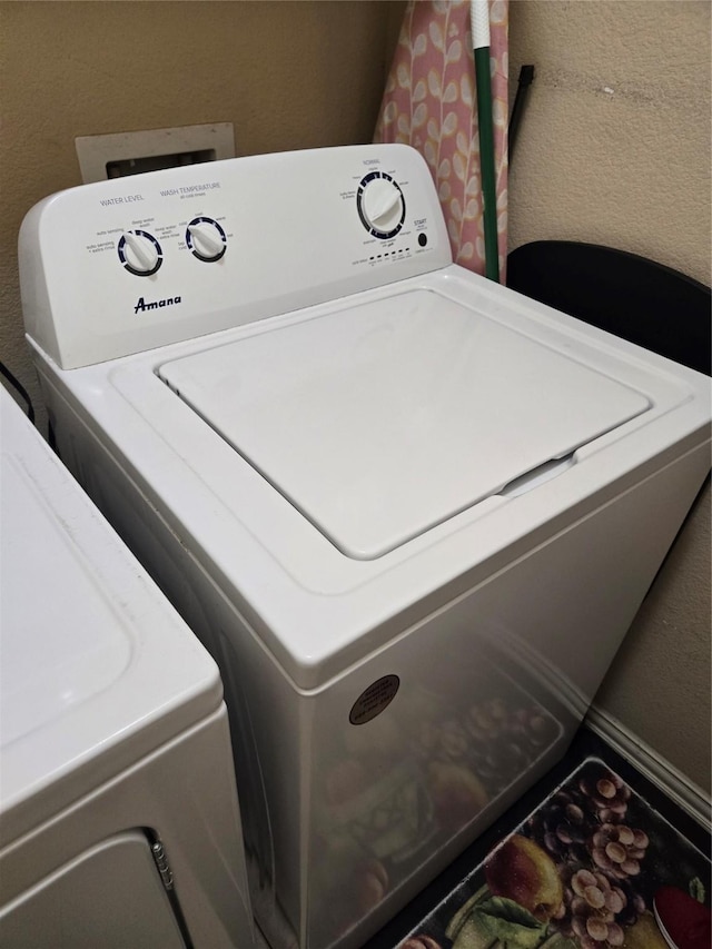 laundry room featuring a textured wall, laundry area, and separate washer and dryer