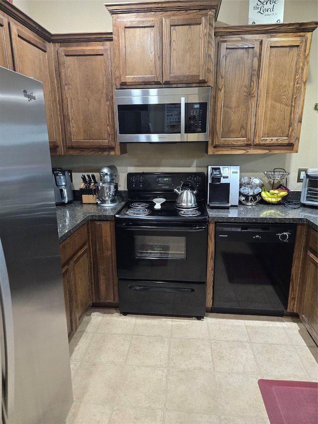 kitchen with black appliances, a toaster, light tile patterned floors, and dark stone countertops