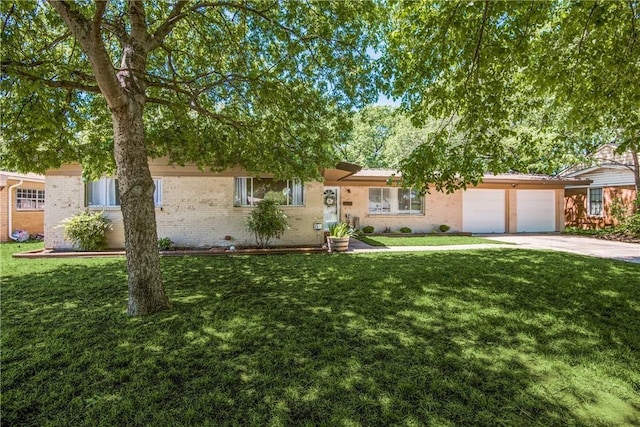 single story home featuring driveway, brick siding, an attached garage, and a front yard