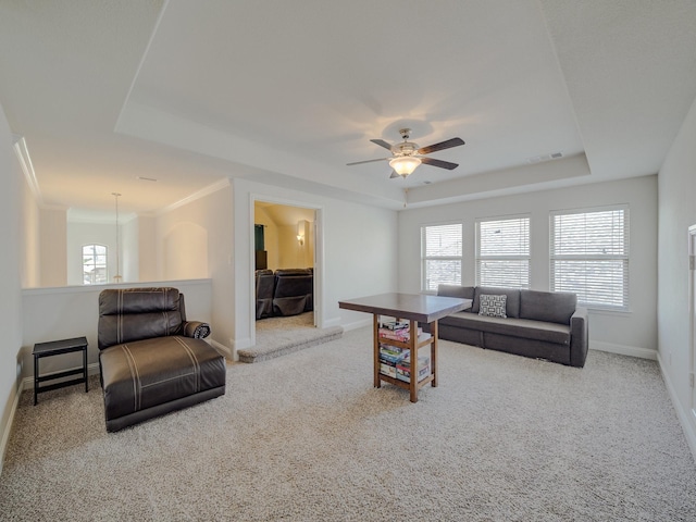 living room featuring baseboards, visible vents, a tray ceiling, and light colored carpet