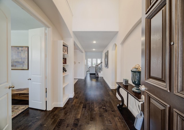 foyer entrance with dark wood-style flooring, stairway, and baseboards