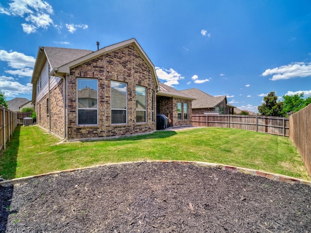 back of property with a yard, brick siding, and a fenced backyard