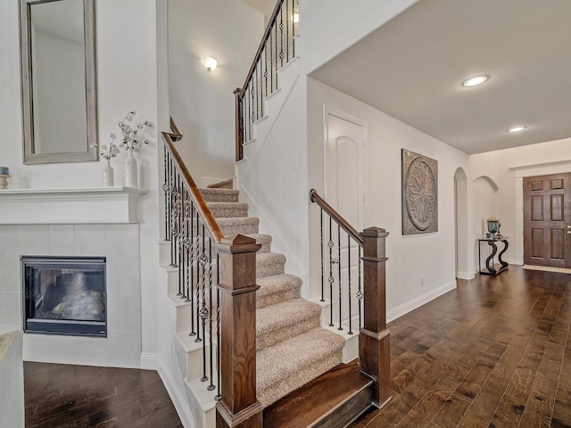 entrance foyer featuring arched walkways, dark wood-style flooring, baseboards, and recessed lighting