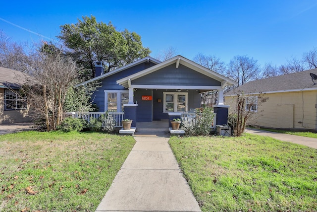 view of front of house featuring a porch, a chimney, and a front lawn